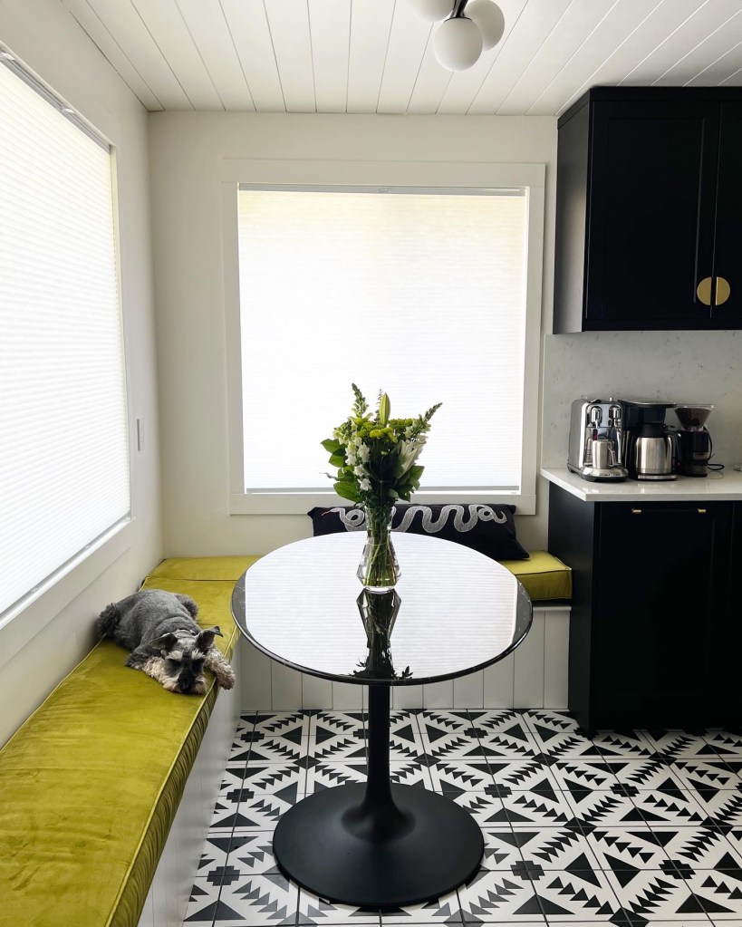 Kitchen dining nook with green velvet bench and oval dining table